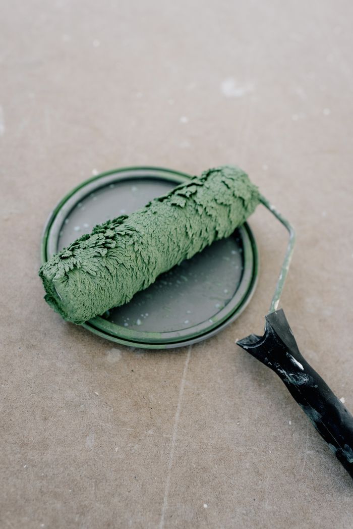 From above of dirty paint roller on green plastic cap on cement floor during repair